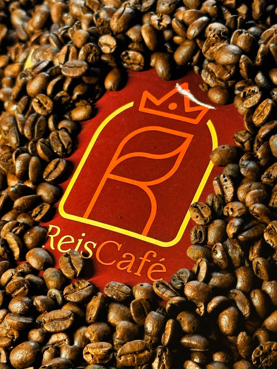 Logo ReisCafé cercado de grãos de café torrados